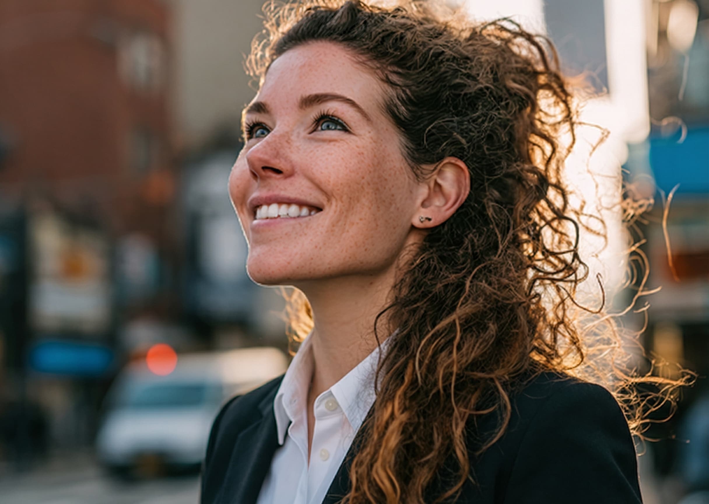 Smiling business leader in a dark blazer looking ahead on a city street
